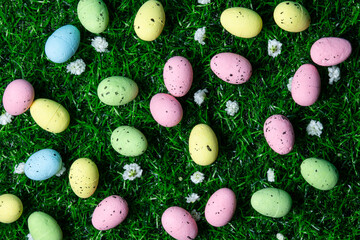 Colorful Easter eggs scattered on green grass with small white flowers at a festive spring celebration