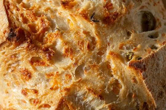 A top down view of a rustic olive sourdough boule, as a background.