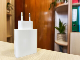 A white power adapter sitting on top of a wooden table