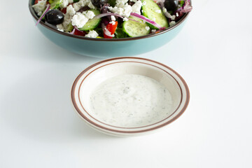 A view of a condiment cup of a creamy Greek dressing.