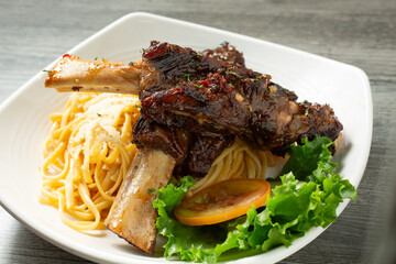 A view of a plate of BBQ beef rib with garlic noodle.