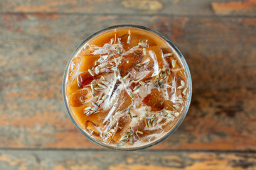 A top down view of a glass of cold lavender honey latte .