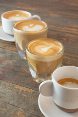 A view of a row of various hot coffee drinks.