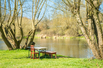 Obraz premium old wooden benches and table near the river Berunka, Czech, in green grass.
