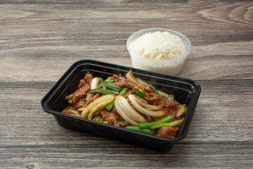 A view of a container of Mongolian beef, with white rice.