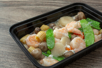 A closeup view of a container of a shrimp with lobster sauce entree.