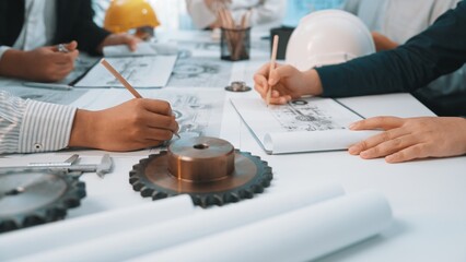 A group of professionals engaged in an engineering meeting, sketching plans on paper with tools surrounding them, showcasing collaboration and creativity in design. SACTR