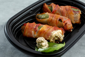 A view of a container of bacon wrapped jalapeno poppers.