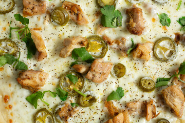 A top down view of a spicy chicken Alfredo pizza, as a background.