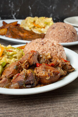 A view of a brown stew chicken, among other entrees.