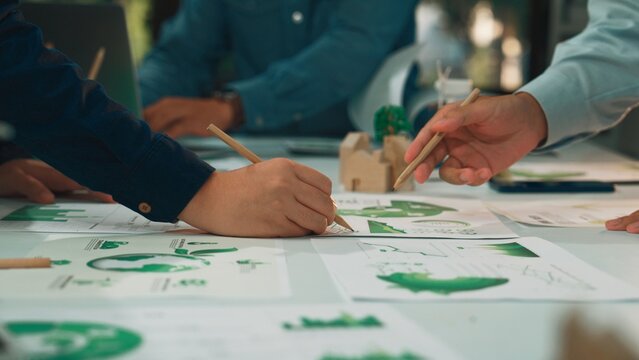 A diverse group of professionals collaborates on environmental reports, analyzing charts and data on the table, showcasing teamwork and effective communication in the office setting. SACTR