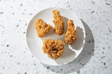 A top down view of 4 pieces of crispy fried chicken, on a plate.