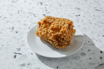 A view of an extra crispy fried chicken thigh, on a plate.
