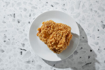 A top down view of an extra crispy fried chicken thigh, on a plate.