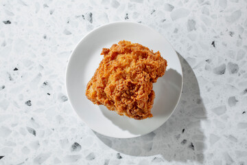 A top down view of a fried chicken thigh, on a plate.