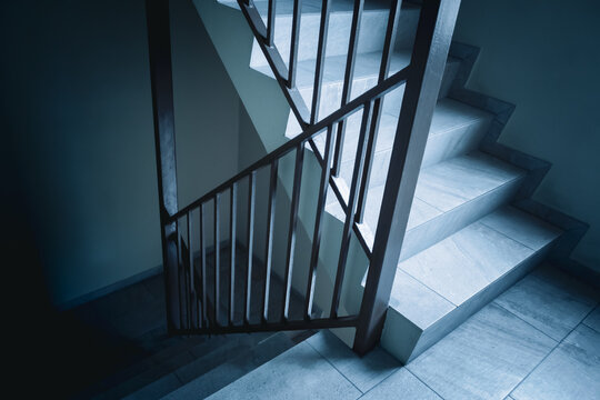 a dimly lit staircase with metal railing and tile steps and light effect background. concept of at a juncture. going up or going down. choices decision design element.