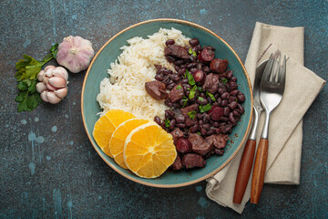 Feijoada, a hearty brazilian stew, with white rice and orange slices, showcasing a vibrant culinary tradition of Brazil alongside garlic and parsley