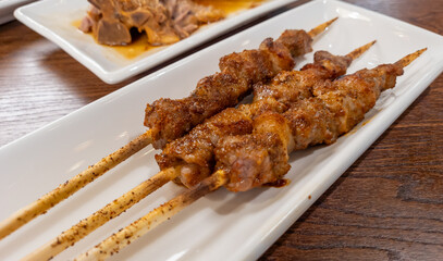 Shaokao, Chinese spiced barbecued meat on skewers, served on a long plate in a restaurant.