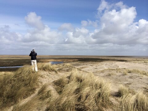 Rear view of a man standing in the sand dunes taking a photo, Fanoe, Jutland, Denmark
