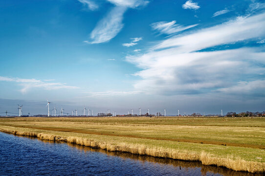 Distant view of wind turbines and Pastureland next to the Lange Maar canal, Oldersum, East Frisia, Lower Saxony, Germany