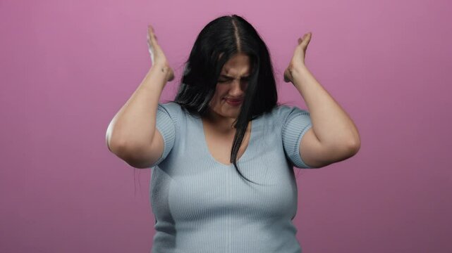 Woman with closed eyes covers ears in stress isolated against vibrant pink wall suggesting frustration or noise.