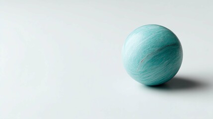 A captivating turquoise sphere sits on a pristine white surface, casting a delicate shadow.