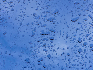 On a clear summer day, raindrops and reflections on the blue metal surface of the hood