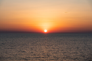 Golden sunset over calm sea with clear horizon and radiant sun. Ideal for background use, wellness, mindfulness, travel inspiration, or peaceful natural themes in visual storytelling.