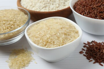 Different types of rice in bowls on table, closeup