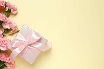 Beautiful bouquet of pink carnations with gift box on a color background
