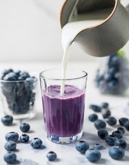 Fresh blueberry smoothie with milk being poured into a glass