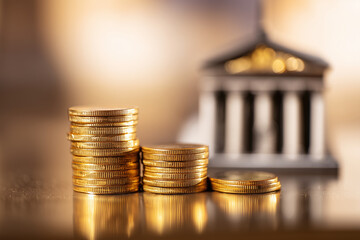 Stack of gold coins increasing in height with blurred government building in background, economic growth and financial institution concept