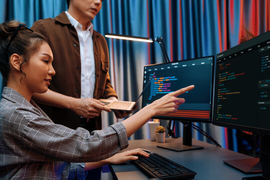 IT developers discussing with point to intelligent website development coder system running data online two screens information technology at neon light room at modern office. Infobahn.