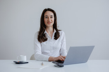 Young professional woman working on laptop in minimalist office setting during daytime