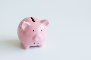 Cute ceramic piggy bank sitting on a white surface with a simple design and smiling expression capturing the essence of saving money