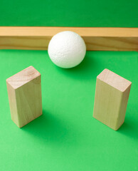 Still life with wooden blocks and a a plastic foam ball on green background	