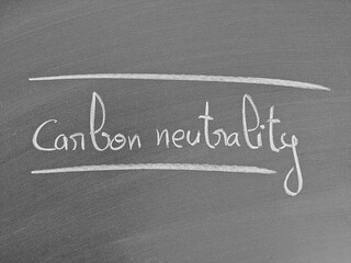 An image displaying the words 'carbon neutrality' handwritten in chalk on a textured slate or...