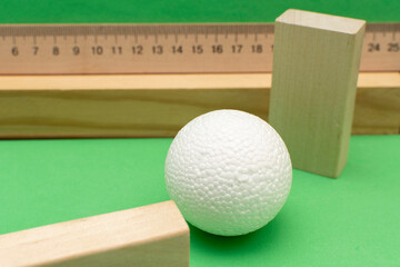 Still life with wooden blocks and a a plastic foam ball on green background
