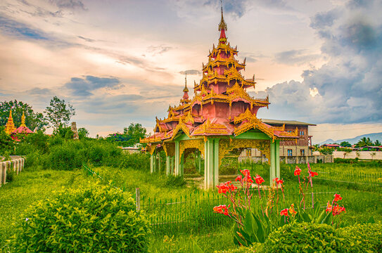 Nyaungshwe, Myanmar, Asia, small Buddhist pagoda at sunset sitting in fenced field.