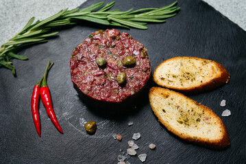Beef tartare with capers and toast on slate.