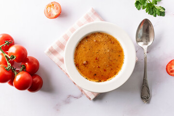 Aromatic spicy cream soup with tomatoes on white marble table top view. Healhy vegan food concept.
