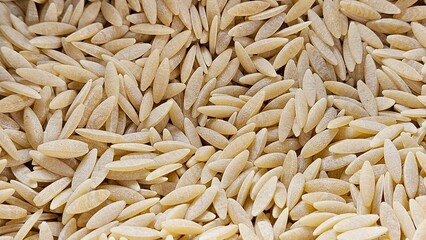 Close up of raw, uncooked orzo pasta. Grainy texture and unique, rice like shape. Healthy food lifestyle, home cooking, culinary, Mediterranean cuisine concept.
