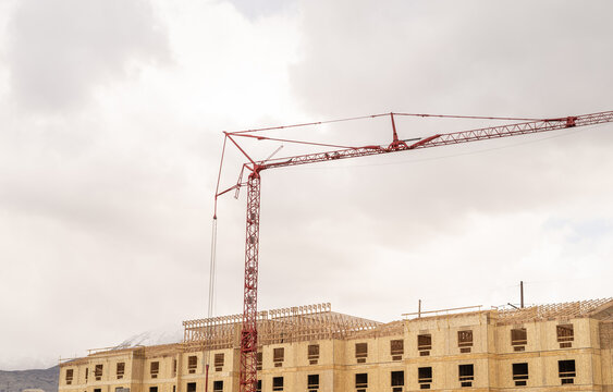 Red tower crane over wooden apartment building construction site new apartments vineyard utah county