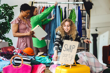 Group of friends generation z girls and boy enjoying home swap party, trying hats, jackets,...