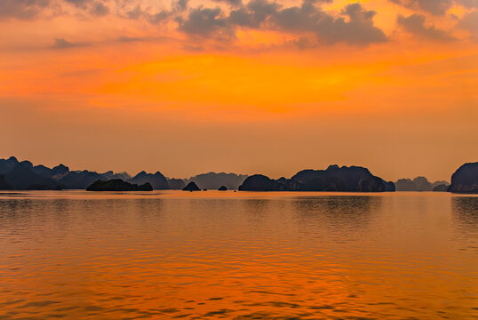Ha Long Bay, Vietnam. Fishing boats at sunset among the limestone karsts and islets, UNESCO Site.