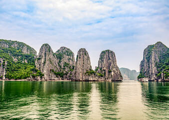 Ha Long Bay, Vietnam. Tourist boat cruising among limestone karsts and islets in turquoise waters.