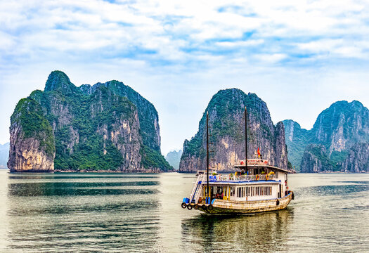Ha Long Bay, Vietnam. Tourist boat cruising among limestone karsts and islets in UNESCO Site.