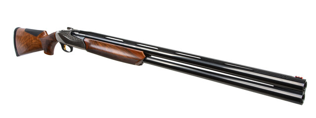 Elegant over-under shotgun with engraved receiver and wooden stock, angled side view on white back