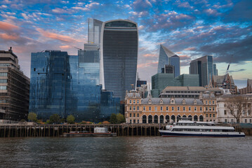 Naklejka premium View of London's skyline featuring the Walkie Talkie and Scalpel buildings, the River Thames, a docked boat, and a historic building in the foreground.