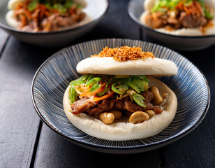 Fototapeta premium Steaming plates of Taiwanese Gua Bao (pork belly buns) with tender pork, pickled vegetables, and peanut powder showcase a popular street food sandwich.